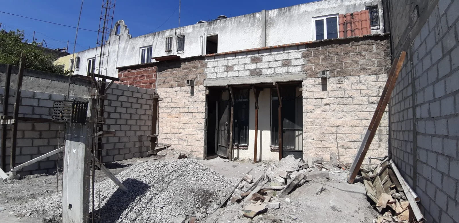 Fachada durante la obra, con muros expuestos y materiales de construcción