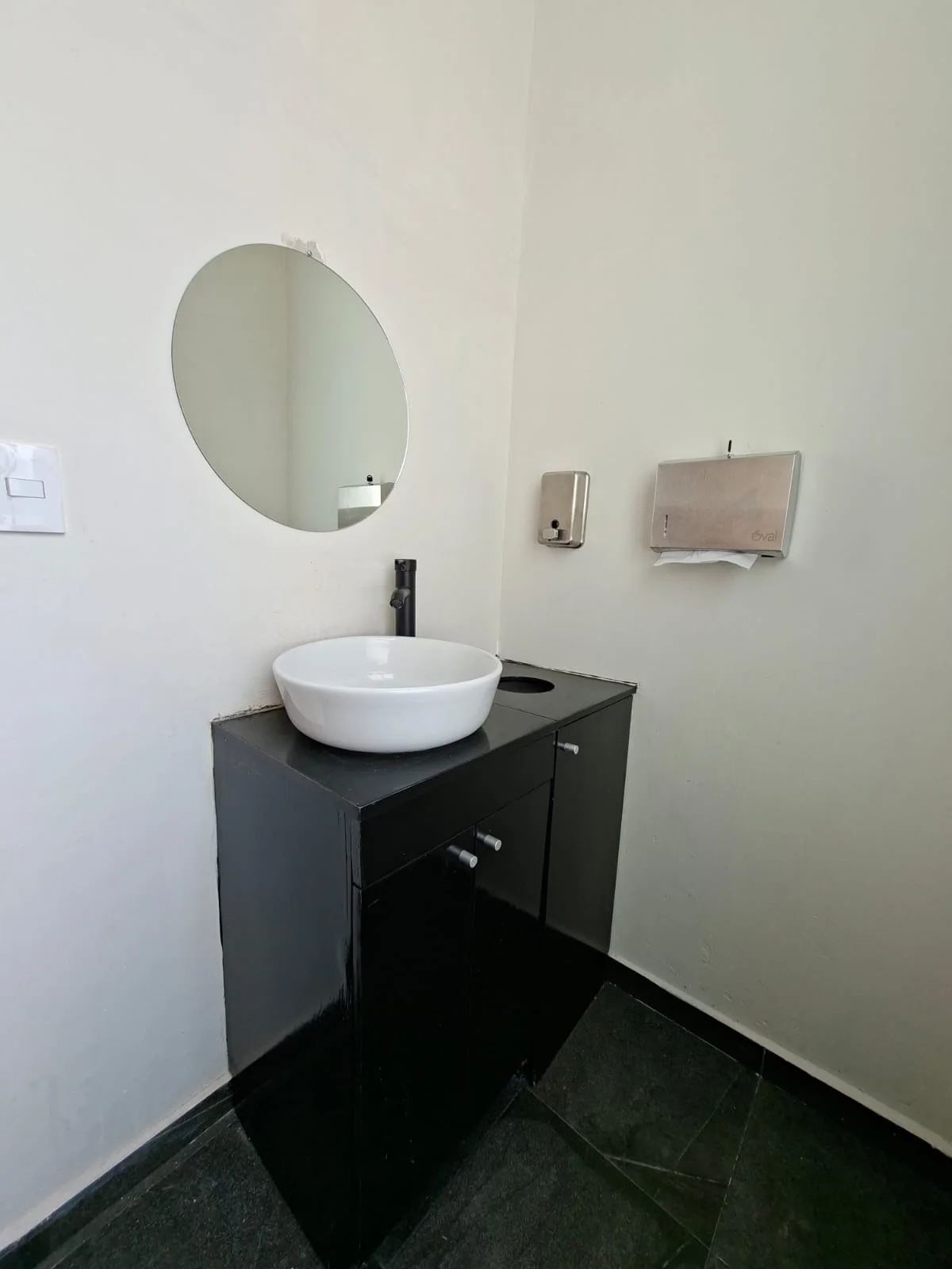 Lavabo sobre mueble oscuro con espejo circular