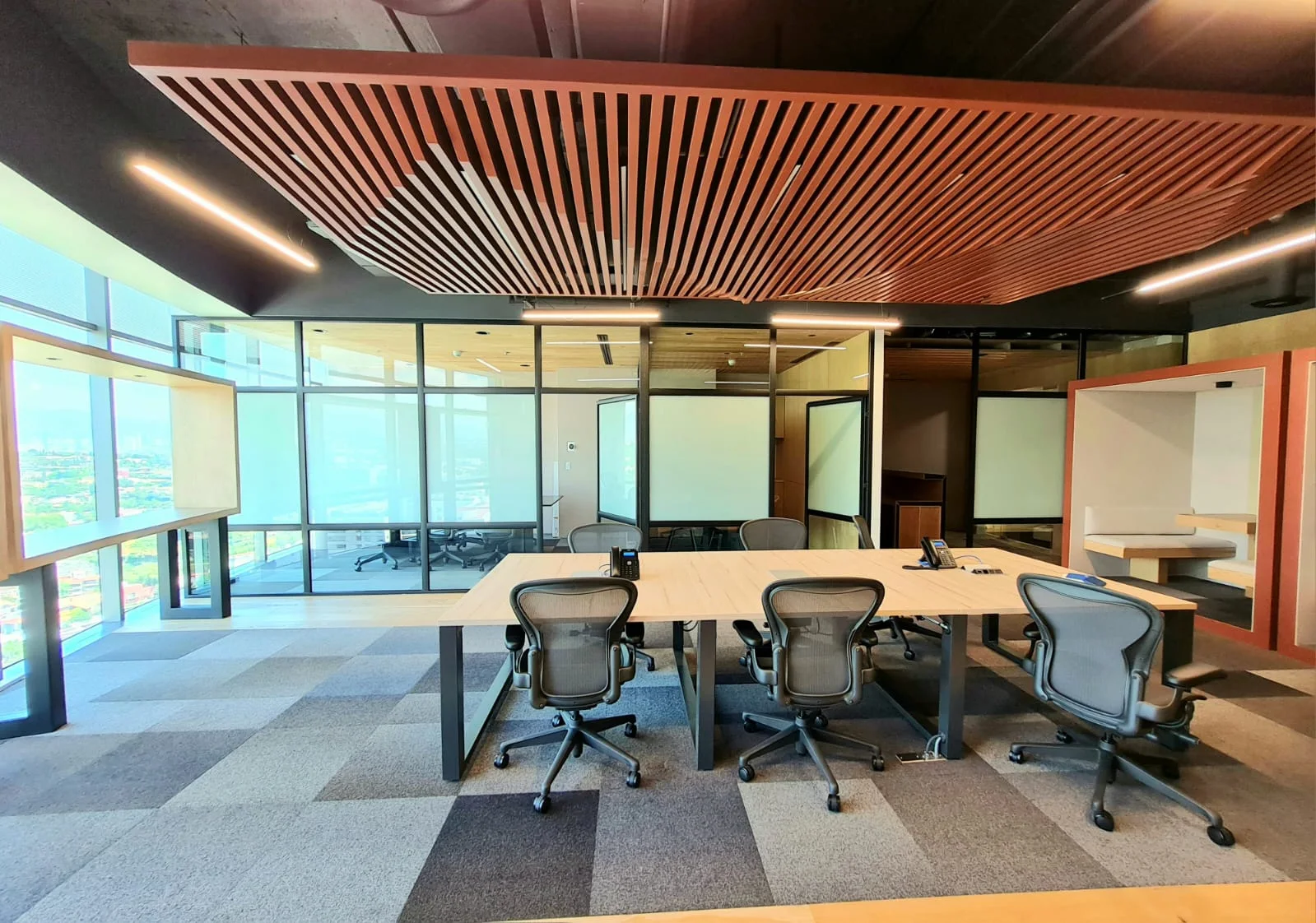 Sala de juntas con mesa central, sillas y plafón de listones de madera
