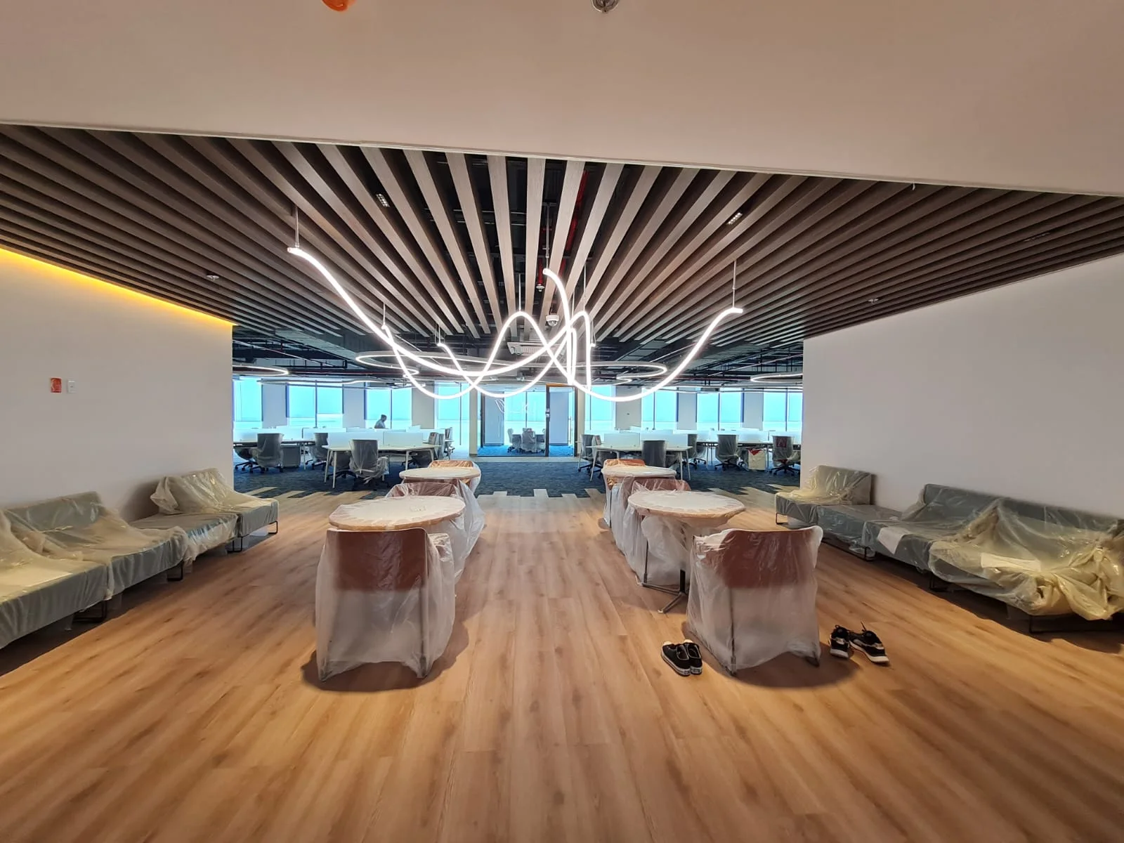 Espacio común de oficinas con mesas altas e iluminación suspendida