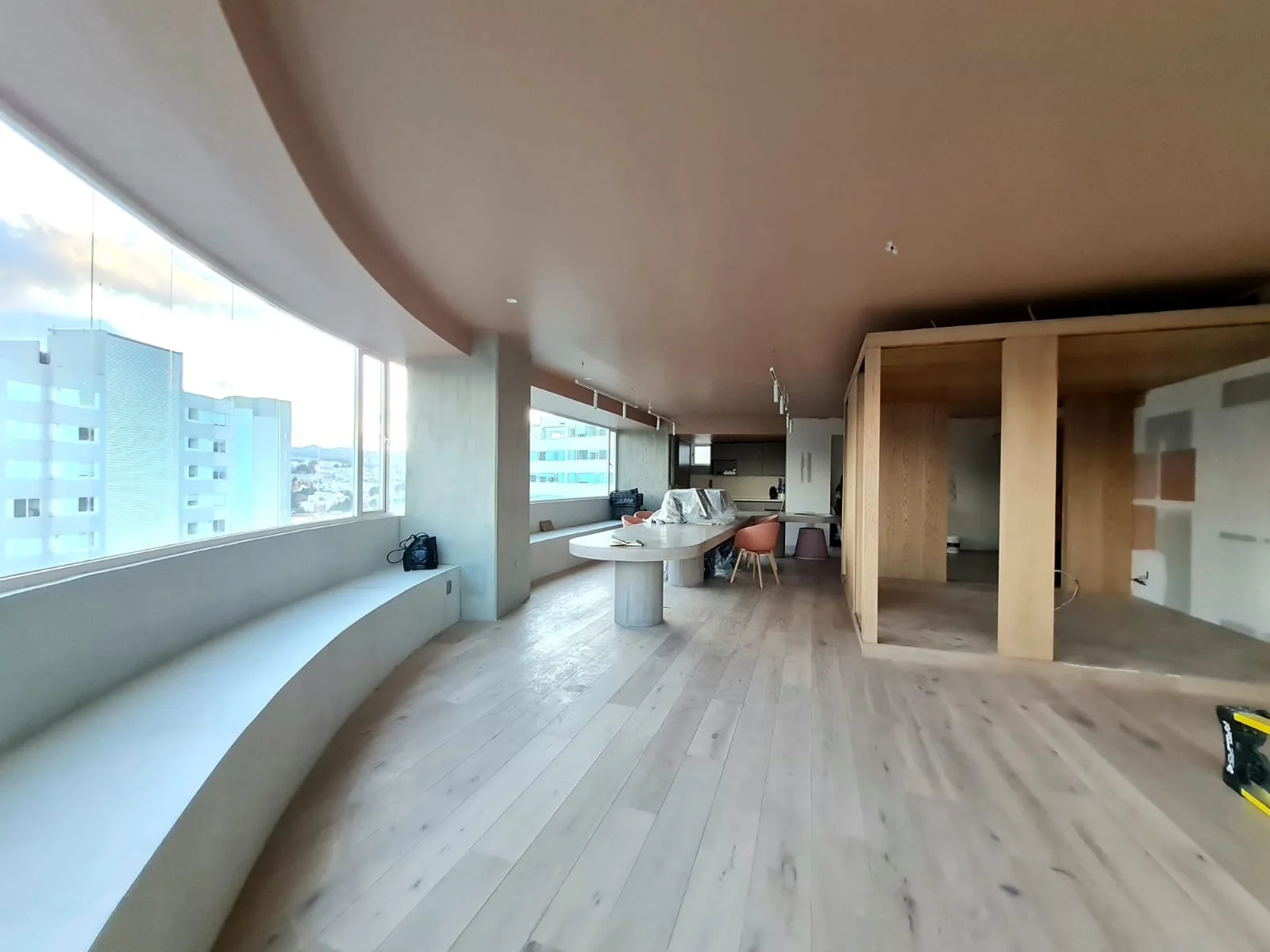 Espacio interior con ventanales curvos y piso de madera